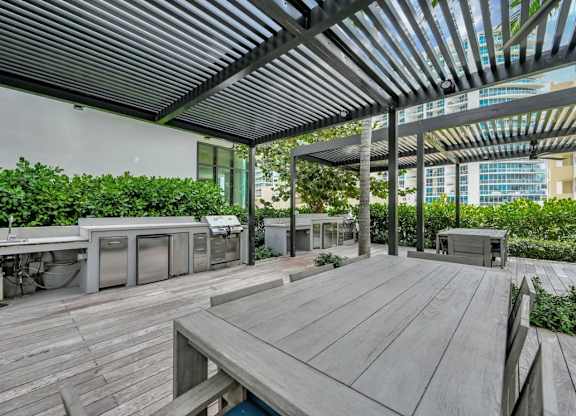 A wooden deck with a table and chairs under a roof.