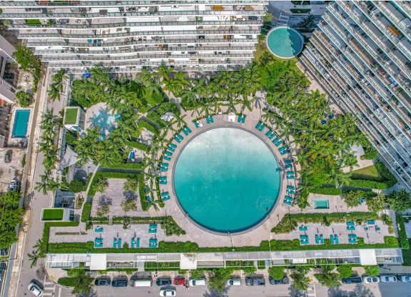 A large round pool surrounded by trees and buildings.