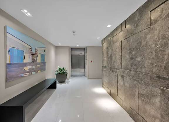 A hallway with a large painting on the wall and a plant on a bench.