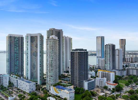 A cityscape with tall buildings and a body of water in the background.