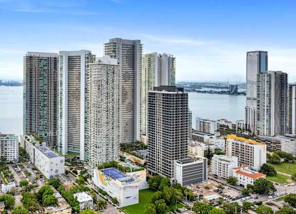 A cityscape with a large body of water in the background and several high-rise buildings.