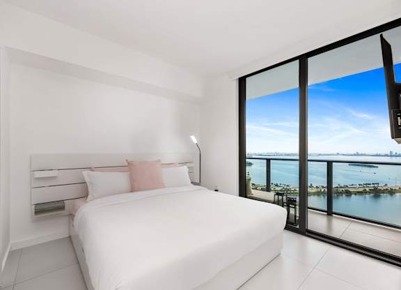 A bedroom with a large bed and a view of the water.
