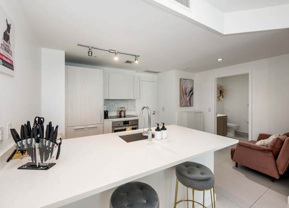 A modern kitchen with white countertops and a large island.