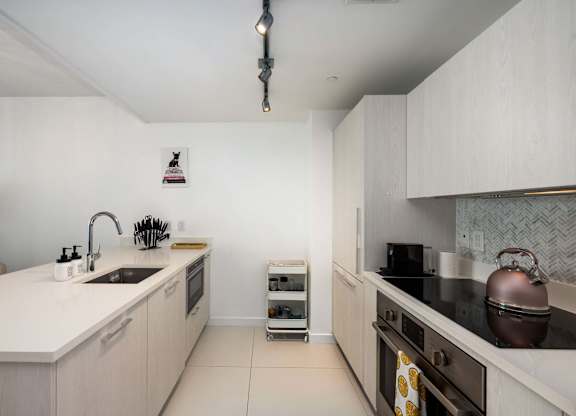 A modern kitchen with a white countertop and stainless steel appliances.