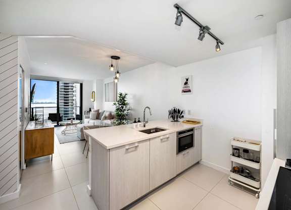 A modern kitchen with a white countertop and wooden cabinets.