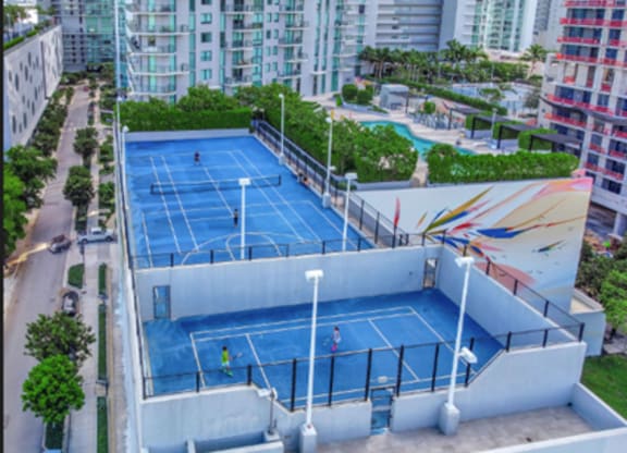 Two people playing tennis on a blue court.
