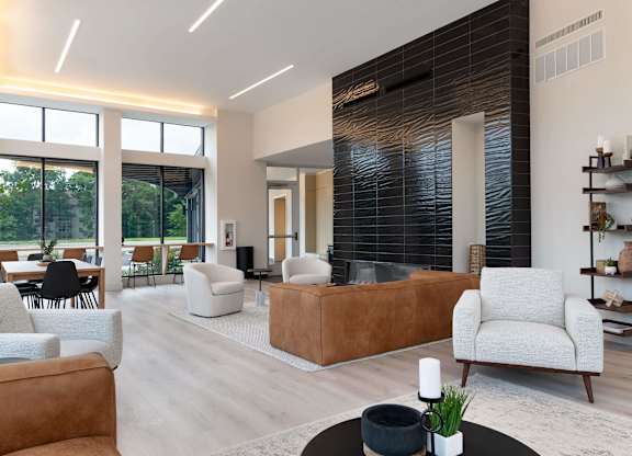 A modern living room with a brown leather couch and a white armchair.