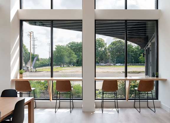 A room with a table and chairs in front of a large window with a view of the outside.
