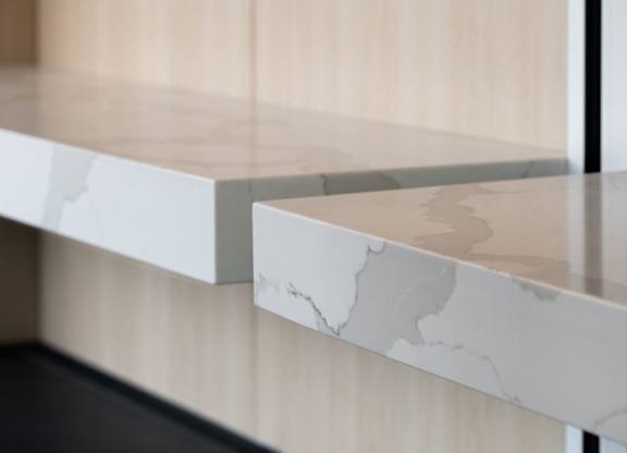 A close up of a white marble shelf with a wooden background.