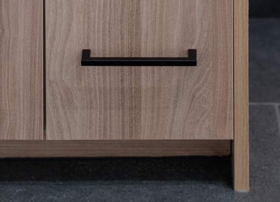 A wooden drawer with a black handle is placed on a grey floor.