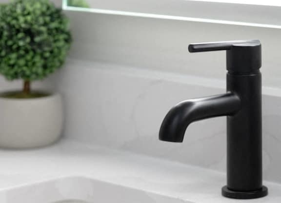 A black faucet is on a white sink.