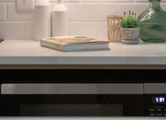 A kitchen counter with a book, two bottles, and a green vase.