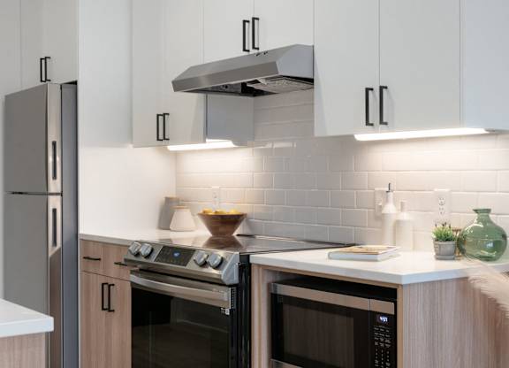 A modern kitchen with a stainless steel refrigerator, a microwave, and a range hood.