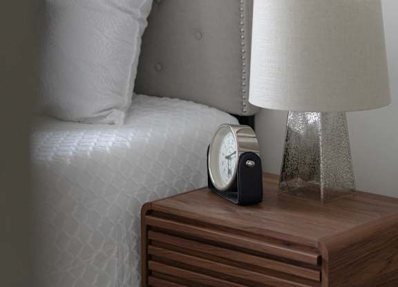 A bedside table with a clock and a lamp.