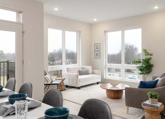 A well-lit living room with a dining table set for two.