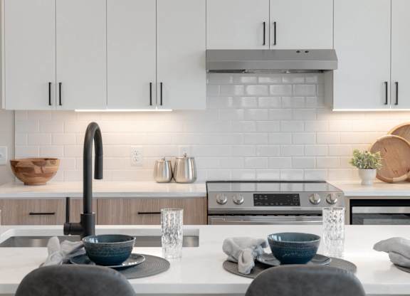 A modern kitchen with a white countertop and a black faucet.