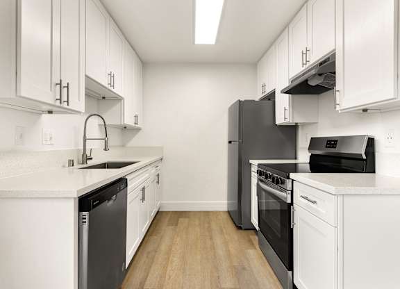 A modern kitchen with white cabinets and black appliances.