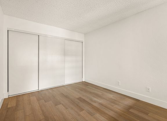 A room with a white wall and a wooden floor.
