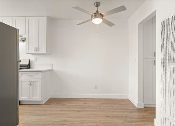 A room with a ceiling fan and a refrigerator.