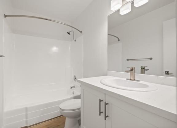 A white bathroom with a toilet, sink, and mirror.