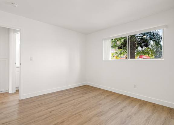 A room with a window and a wooden floor.