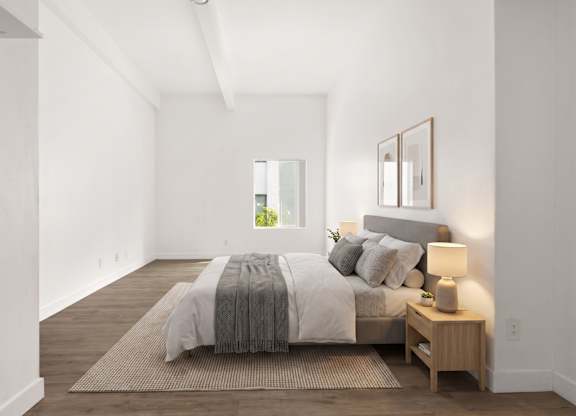 A bedroom with a bed, nightstand, and a window.