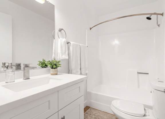 A white bathroom with a toilet, sink, and shower.