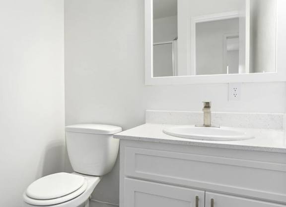 A white toilet sits next to a white sink in a bathroom.