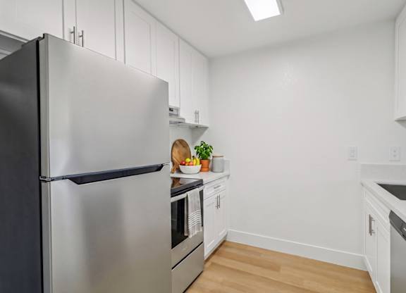 A kitchen with a black refrigerator and white cabinets.