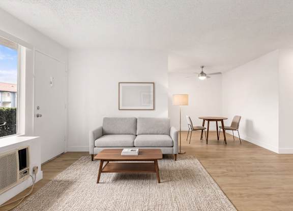 A living room with a grey couch, a brown coffee table, and a painting on the wall.