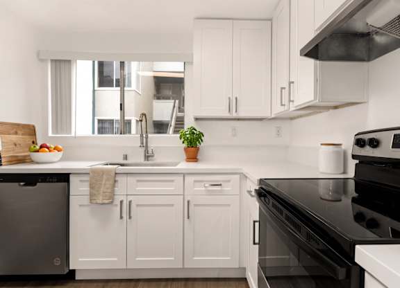 A modern kitchen with white cabinets and black appliances.