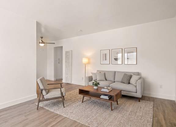 A living room with a grey couch, a chair, a coffee table, and pictures on the wall.