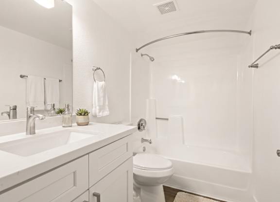 A white bathroom with a toilet, sink, and bathtub.