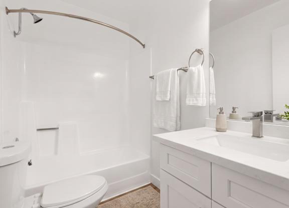 A white bathroom with a toilet, sink, and bathtub.