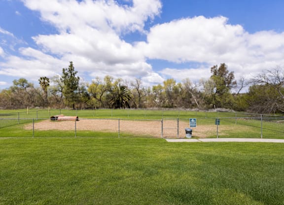 A baseball field with a fence and a sign in the distance.