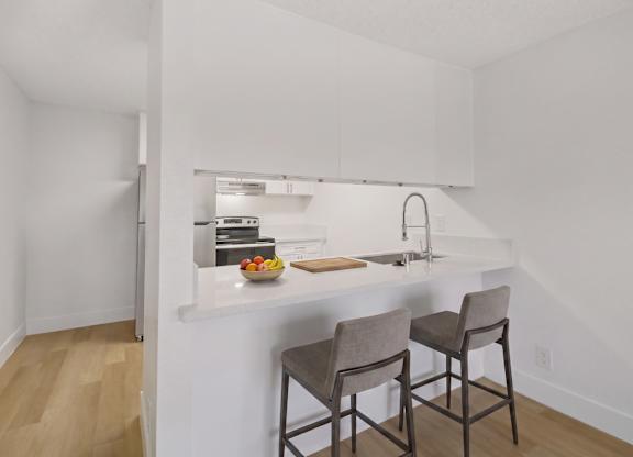 A kitchen with a white counter top and two chairs.