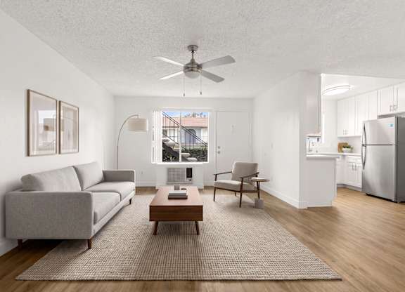 A living room with a grey couch, a brown coffee table, and a ceiling fan.