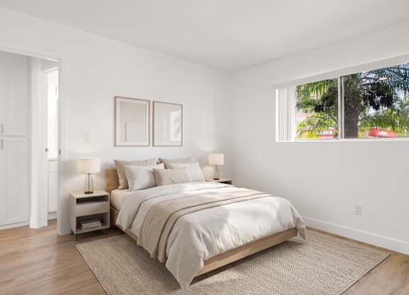A bedroom with a large bed, two nightstands, and a window.