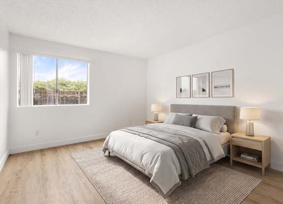 A bedroom with a large bed and a window overlooking a fence.