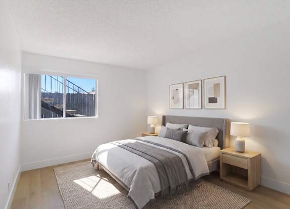 A bedroom with a large bed and a window overlooking a fence.