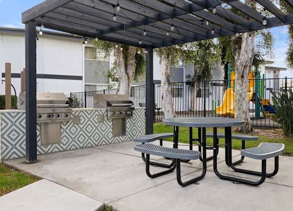 A picnic area with a grill and a table under a canopy.