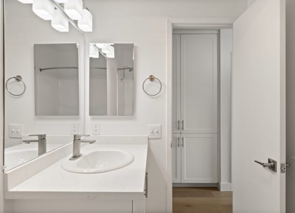 A white bathroom with a sink and mirror.