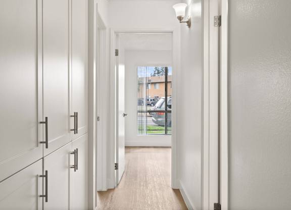 A long hallway with white doors and a light on the wall.