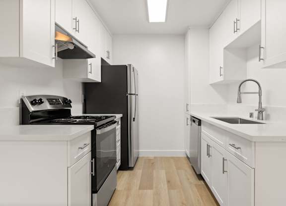 A kitchen with black appliances and white cabinets.