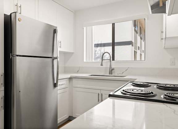 A modern kitchen with a stainless steel refrigerator and a white countertop.