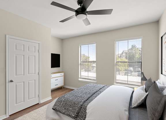A bedroom with a large bed and a ceiling fan.