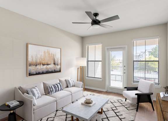 A living room with a grey couch, a coffee table, a chair, and a painting on the wall.