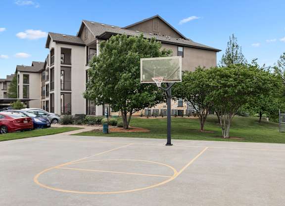 A basketball court is located in front of a large apartment building.
