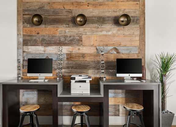 A wooden desk with two computers and a printer on it.
