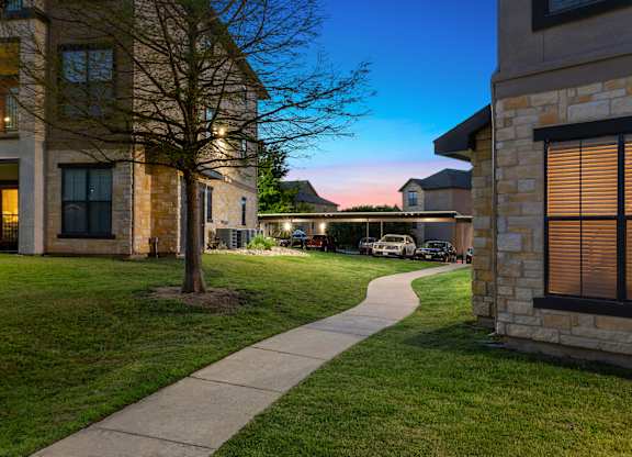 A tree stands in a grassy area in front of a building.